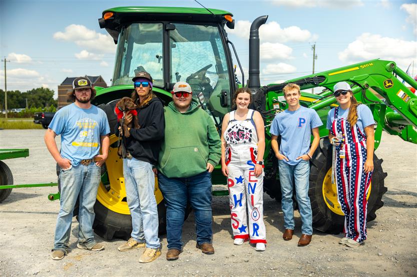 Six students stand in front of a tractor